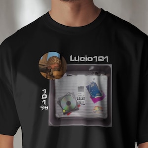 Könnte beinhalten: Schwarzes T-Shirt mit einem weißen Grafikdesign. Die Grafik zeigt eine weiße Box mit einem blau-weiß gemusterten Notizbuch, einer CD und einem weißen Papier mit dem Text "101". Der Text "Lucio101" befindet sich über der Box. Im oberen linken Eck befindet sich ein kleines Bild einer Person mit Hut.