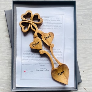 May include: A wooden lovespoon with three carved hearts, each with a name inscribed: Oscar, Shae, and Piper. The lovespoon is in a grey box with a note that reads: "Hi my name is Matt..."