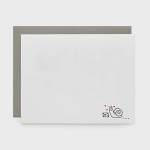 May include: A white card with a gray border featuring a whimsical illustration of a snail delivering a letter. The snail is drawn in black ink with a dotted trail, hearts, and an envelope.