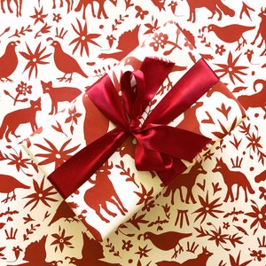 May include: A red and white gift wrap with a red ribbon. The pattern features stylized animals, flowers, and geometric shapes.