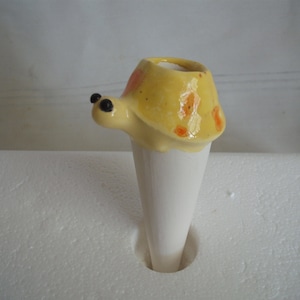 May include: A yellow ceramic turtle planter with orange spots and black eyes. The planter is shaped like a turtle shell and has a hole in the top for planting.