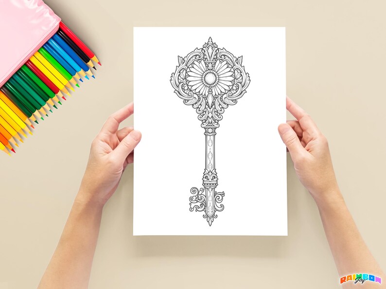 Photo of a grayscale key coloring page printed on paper, held by two hands. Colorful pencils are arranged in the background, showing the creative potential of the coloring pages for both kids and adults.