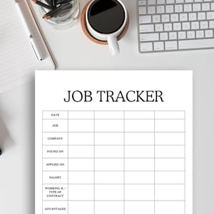 May include: A white printed job tracker sheet with the title "JOB TRACKER" at the top. The sheet has sections for date, job, company, and salary. A cup of coffee, a keyboard, and a notepad are also visible.