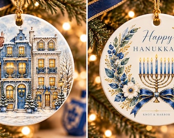 May include: A round ceramic ornament featuring a snowy European street scene with lit windows on one side and a gold menorah with blue candles surrounded by a blue and white floral wreath and the text Happy HANUKKAH KNOT & HARBOR on the other.