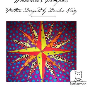 以下が含まれることがあります： 星形のデザインが施されたカラフルな布のキルトブロック。星は黄色、赤、オレンジ、紫、黒の布で作られています。背景の布は濃い紫で、青い水玉模様です。画像の上部には「Mariner's Compass」と「Pattern Designed by Danika Noey」のテキストがあります。