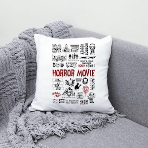 Peut inclure: Coussin carr&eacute; blanc avec un collage de texte et de graphiques noirs et rouges sur le th&egrave;me des films d'horreur. Le texte comprend des phrases telles que "Horror Movie", "Horror Addict" et "What's Your Favorite Scary Movie ?". Le coussin est sur un canap&eacute; gris.