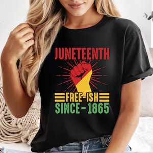 May include: Black t-shirt featuring the word "Juneteenth" in red, above a fist graphic with red and yellow. Below, the text "FREE-ISH SINCE-1865" is displayed in green and yellow.