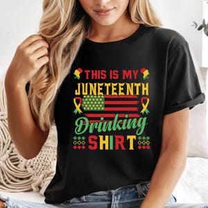 Puede incluir: Camiseta negra con un diseño gráfico colorido. El diseño incluye el texto "THIS IS MY JUNETEENTH DRINKING SHIRT" con un motivo de la bandera estadounidense, cintas amarillas y elementos decorativos.