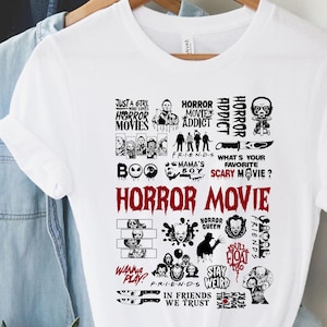Peut inclure: T-shirt blanc avec un motif graphique comportant les mots "HORROR MOVIE" en grandes lettres rouges. Le motif comprend diverses images et phrases sur le th&egrave;me de l'horreur, comme "HORROR ADDICT" et "Wanna Play?"