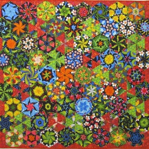 Puede incluir: Una colcha colorida con un patrón geométrico de hexágonos y triángulos. La colcha está hecha de varias telas con diseños florales y geométricos en tonos de rojo, verde, azul, amarillo y blanco.