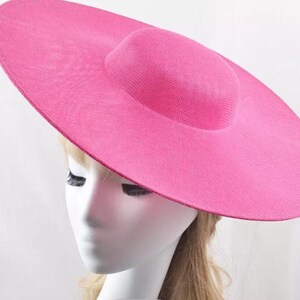 May include: A large, wide-brimmed hat in a bright pink color. The hat has a slightly rounded crown and a wide, flat brim.