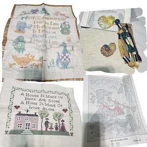 May include: A collection of vintage cross-stitch projects. Includes completed pieces with embroidered images and text, and patterns with thread. One piece features a house and family, another a prayer, and a third a boy blowing a horn.