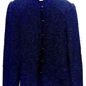 May include: A dark blue knitted cardigan with a button closure and two pockets. The cardigan has a textured knit pattern.