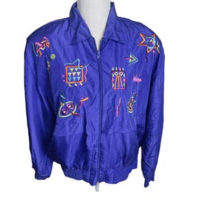 May include: A vintage blue jacket with a zip-up front and a collared neckline. The jacket features colorful embroidered abstract designs in pink, orange, yellow, and green. The jacket has long sleeves and a relaxed fit.
