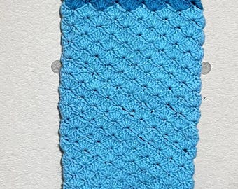 Op de afbeelding: Een gehaakte mermaid-staartdeken in tinten blauw. De staart is gemaakt van een getextureerd garen en heeft een gegolfde rand.