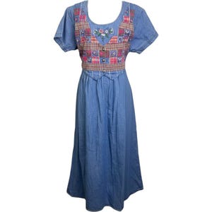 May include: A blue denim midi dress featuring short sleeves and a scoop neckline. The bodice displays a patchwork-style panel with red, pink, and blue plaid and floral patterns, accented by three metal buttons and embroidered floral details.