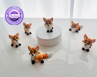 May include: Six small orange and white fox figurines with large eyes and black paws. One fox stands on a white circular platform, while the other five are arranged around it. Each fox features a bushy tail and a white chest patch, with a purple logo.