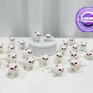 May include: A collection of white cat figurines with pink accents on their ears and noses. The cat figurines have black eyes and long tails. Some are standing, and some are sitting. The figurines are arranged on a white surface.
