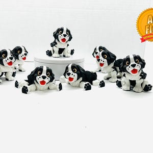 May include: A set of eight black and white dog figurines with red noses. The figurines are in various poses, including sitting, standing, and lying down. The figurines are made of a soft, flexible material.