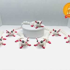 May include: A set of eight white, bendable, plush toys shaped like sugar gliders. The toys have pink noses, pink ears, and black eyes. The toys are arranged in a circle on a white surface.