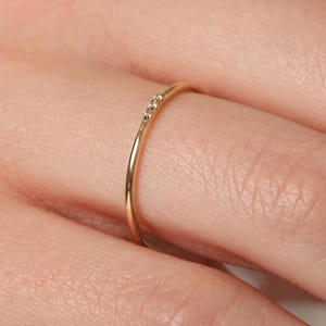 May include: A delicate gold band ring with three small diamonds set in a row.