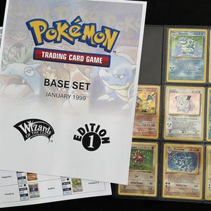 May include: A binder with Pokémon Trading Card Game cards from the Base Set, January 1999. The cover features the Pokémon logo and illustrations of Blastoise and Charizard. The binder contains various cards, including Blastoise, Chansey, and Charizard.