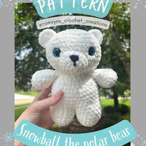May include: A white crocheted polar bear named Snowball with blue eyes and a black nose. The image includes the text "PATTERN" and "Snowball the polar bear". The bear is handmade and has a soft, textured appearance.