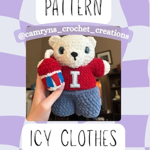 Puede incluir: Un oso blanco de ganchillo con un suéter rojo con una "I" blanca y pantalones azules, sosteniendo un artículo rojo, blanco y azul. La imagen incluye el texto "PATTERN", "@camryns_crochet_creations" y "ICY CLOTHES".