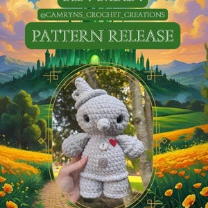 Puede incluir: Muñeco de ganchillo gris del Hombre de Hojalata con detalles de botones y un corazón rojo. La imagen incluye el texto "TIN MAN" y "PATTERN RELEASE". El fondo presenta un paisaje con un camino de ladrillos amarillos y un castillo verde.