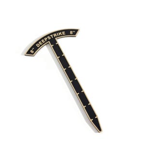 May include: A black T-shaped tool with gold trim and gold lettering that reads 8" DEEPSTRIKE 8". The vertical shaft features evenly spaced gold markings along its length, and the curved top section also displays the 8" measurement text.