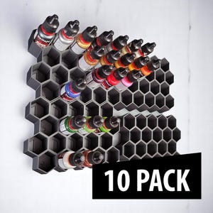 May include: A dark gray, honeycomb-shaped paint bottle organizer holding multiple bottles of paint. The bottles are filled with various colors, including red, yellow, blue, and green. The text "10 PACK" is displayed in a black rectangle.