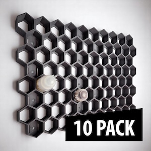 Peut inclure: Un organisateur mural en forme de nid d'abeilles gris foncé avec deux bouteilles transparentes à l'intérieur. L'organisateur est en plastique et présente un motif hexagonal répétitif. Le texte "10 PACK" est affiché dans un rectangle noir.