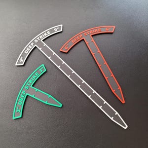 May include: Three black plastic measuring tools with white markings. The tools are shaped like a T and have different lengths: 3 inches, 6 inches, and 9 inches. The tools are labelled "DEEP STRIKE" with the corresponding length in inches.