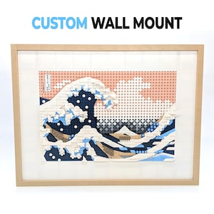 May include: A rectangular wall mount constructed from interlocking plastic building bricks, featuring a mosaic recreation of The Great Wave off Kanagawa. The artwork is framed in tan bricks with a white border and includes the text CUSTOM WALL MOUNT.
