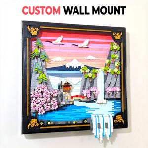 May include: A custom wall mount featuring a Japanese landscape scene constructed from colorful building blocks. The scene includes a mountain, waterfall, cherry blossoms, and flying birds, all framed in a black border with gold accents. The text "CUSTOM WALL MOUNT" is at the top.