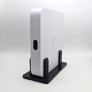 May include: A white rectangular device with rounded edges, standing upright on a black stand. The device has a small oval opening and a stylized "C" logo. The text "Cloud Gateway Ultra" is printed vertically on the side.