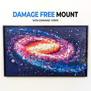 May include: A rectangular wall art piece constructed from small plastic building bricks, depicting a spiral galaxy in shades of pink, orange, purple, and blue. The text DAMAGE FREE MOUNT WITH COMMAND STRIPS is printed above the framed artwork.