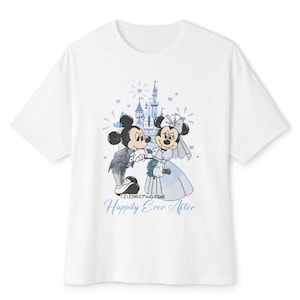 May include: White t-shirt featuring a graphic of Mickey and Minnie Mouse in wedding attire, with a castle backdrop. The design includes the text "Celebrating Our Happily Ever After" in blue script. The shirt is a classic crew neck style.