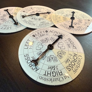 May include: Four circular game boards with black hands and white faces. The boards have text and illustrations, including the words "LEFT", "RIGHT", and "ACROSS". The boards are for a game, possibly Mahjong.