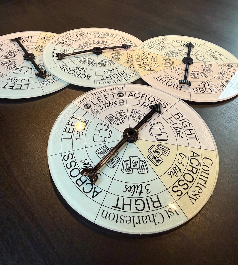 May include: Four circular game boards with black hands and white faces. The boards have text and illustrations, including the words "LEFT", "RIGHT", and "ACROSS". The boards are for a game, possibly Mahjong.