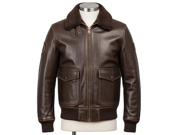 May include: A brown leather bomber jacket with a shearling collar, two front pockets, and a ribbed hem and cuffs. The jacket has a zip-up closure and is displayed on a mannequin.