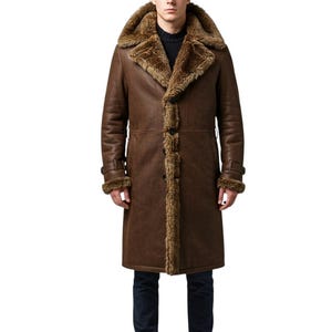 May include: A long, brown shearling coat with a large, fur-lined collar and cuffs. The coat has a button-up front and a tailored fit. The model is wearing black trousers. This outerwear is suitable for cold weather.