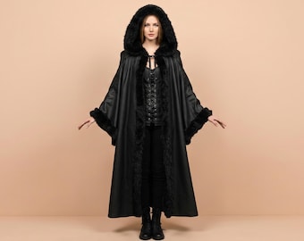 May include: A floor-length black cloak featuring a hood and wide sleeves trimmed with black faux fur. The garment is fastened at the neck with a decorative clasp and is worn over a black lace-up bodice and black trousers, creating a layered look.