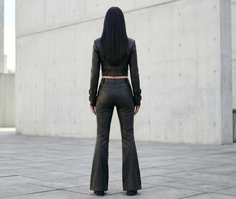 May include: A black leather outfit consisting of a cropped long-sleeve jacket and matching flared trousers. The jacket features long sleeves with buckled cuffs, while the trousers have a fitted waist and a flared leg silhouette from the knee down.