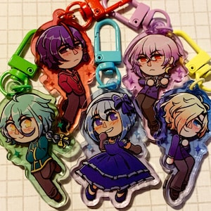 Può includere: Una collezione di portachiavi colorati con personaggi in stile anime. Ogni portachiavi presenta un design unico del personaggio con colori vivaci ed è attaccato a un fermaglio di metallo. I portachiavi sono realizzati in acrilico trasparente.