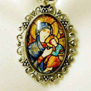 May include: Silver-toned pendant necklace featuring an oval pendant with a religious image. The pendant has a decorative filigree border and a chain. The image depicts a woman and child in shades of blue, gold, and red.