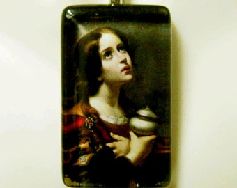 May include: Silver-toned chain necklace with a rectangular pendant featuring a classical painting of a woman looking upwards. The painting depicts a woman in a red and gold dress holding a white and gray vessel. The pendant is rectangular with a silver bail.