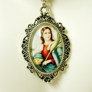 May include: Silver pendant necklace with a cameo featuring a woman in a blue and red dress holding a branch. The cameo is surrounded by an ornate silver frame.