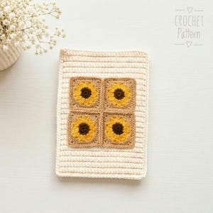 Puede incluir: Una pieza rectangular de ganchillo en color blanco roto con cuatro motivos cuadrados de girasoles en el centro, cada uno con un centro marrón oscuro y pétalos amarillos. El texto CROCHET Pattern aparece en la esquina superior derecha.