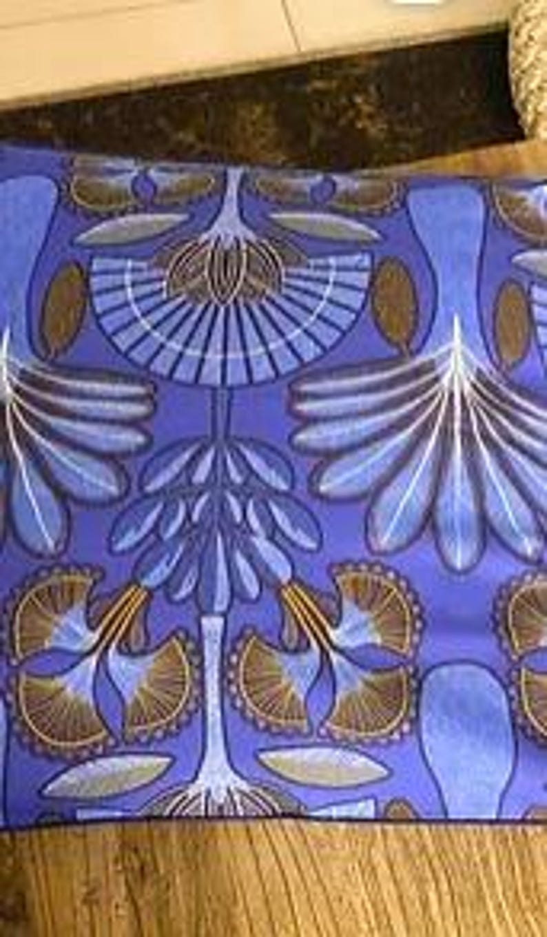 May include: Blue fabric with a repeating pattern of stylized trees with brown branches and white leaves. The background is a solid blue.